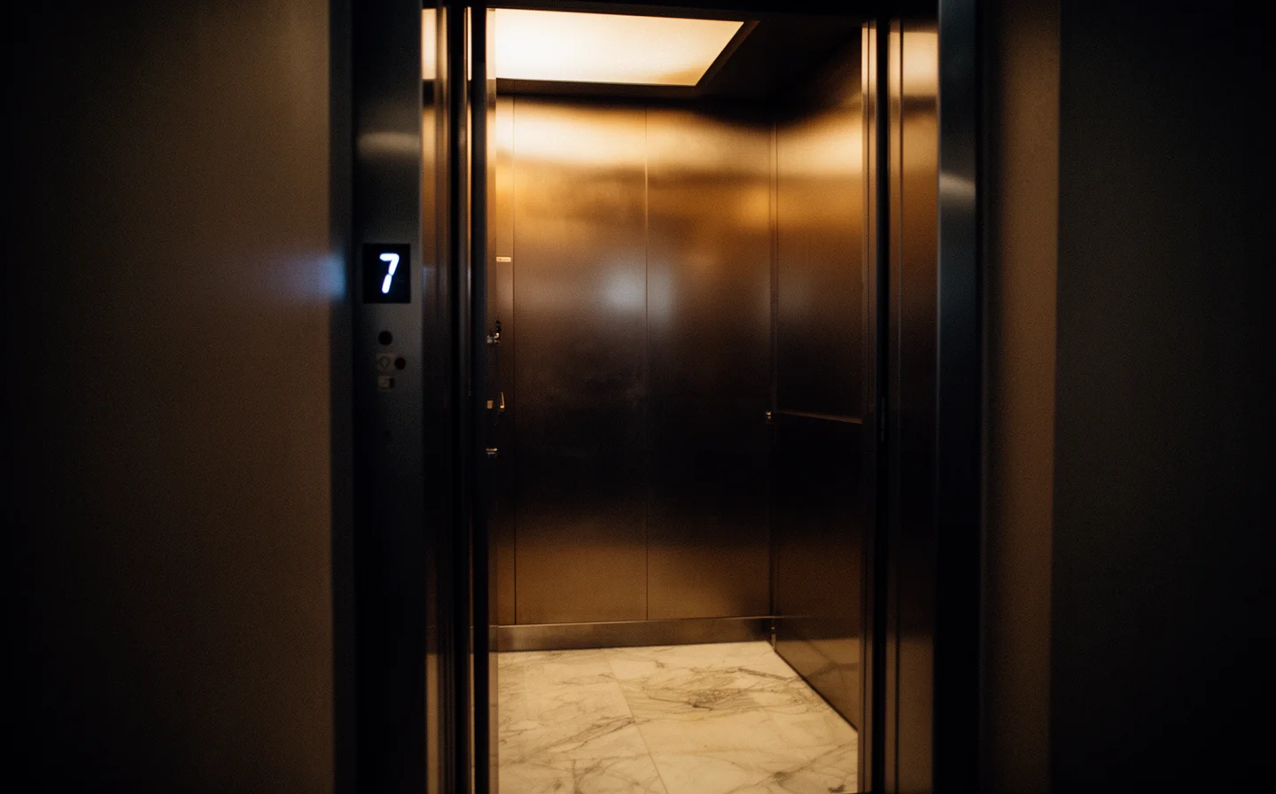 Empty elevator interior with warm amber light, floor indicator showing 7